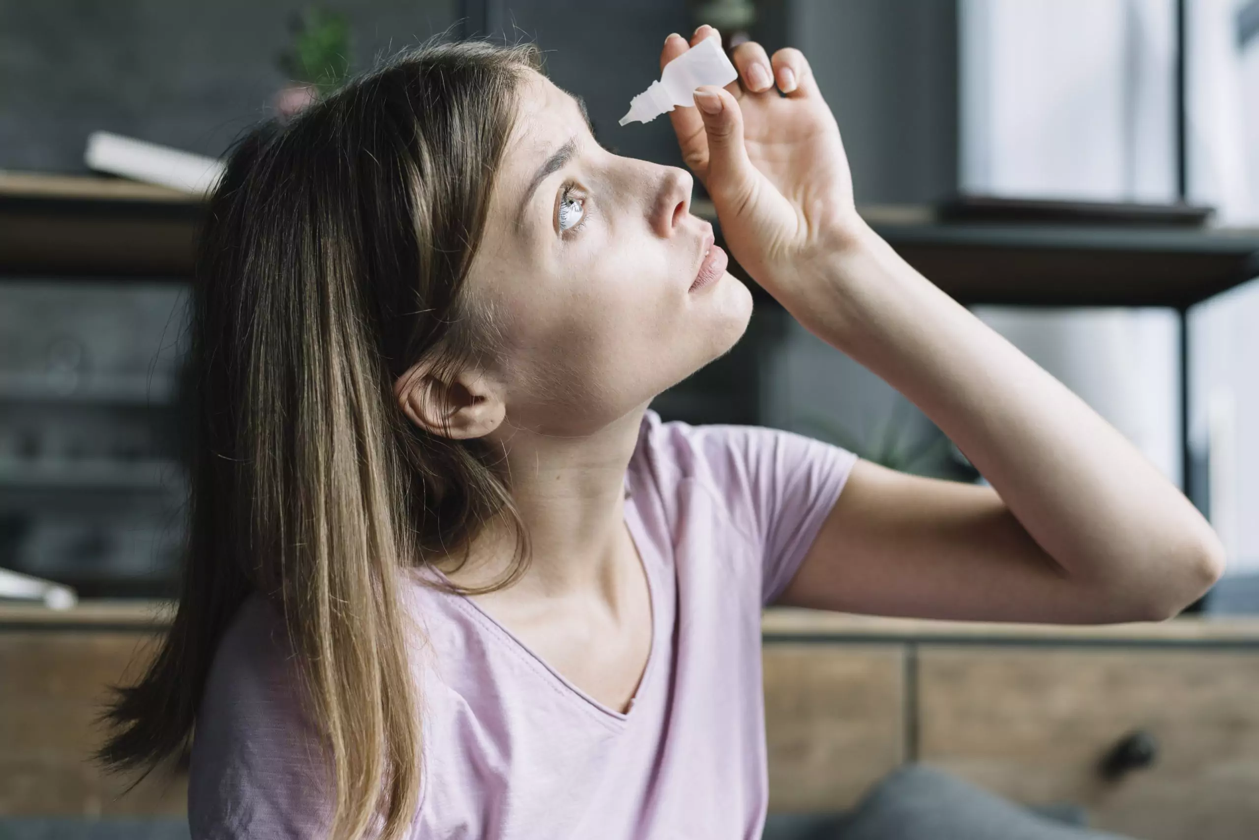 Young woman putting in eye drops for glaucoma treatment