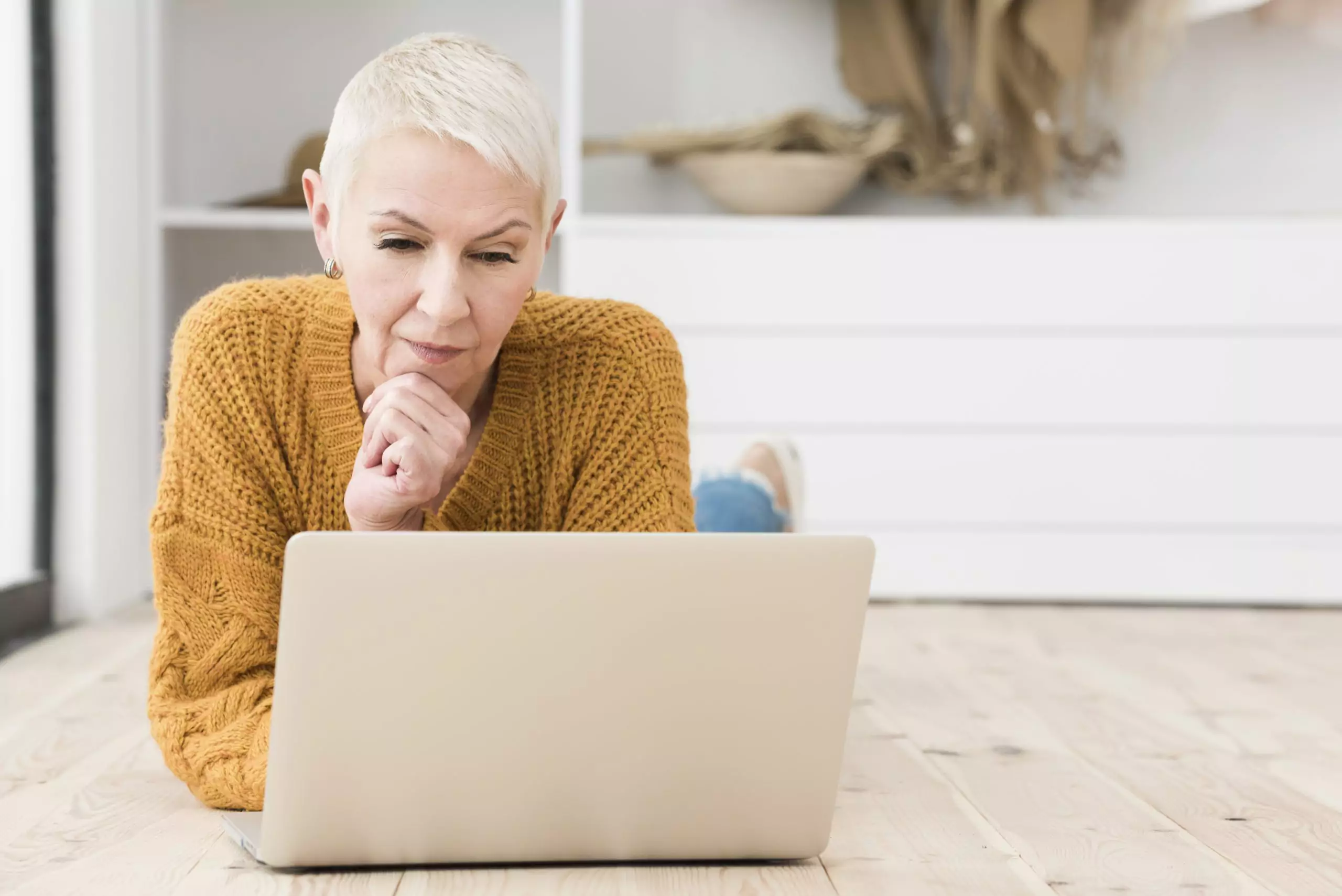 Older woman laying on floor looking at laptop considering second opinion on fibroids