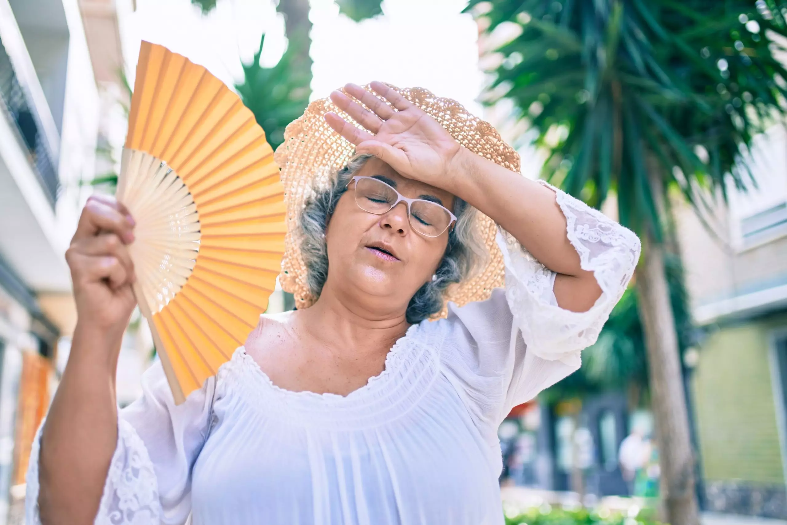 Middle Age Woman With Grey Hair Using Handfan To Cool Down